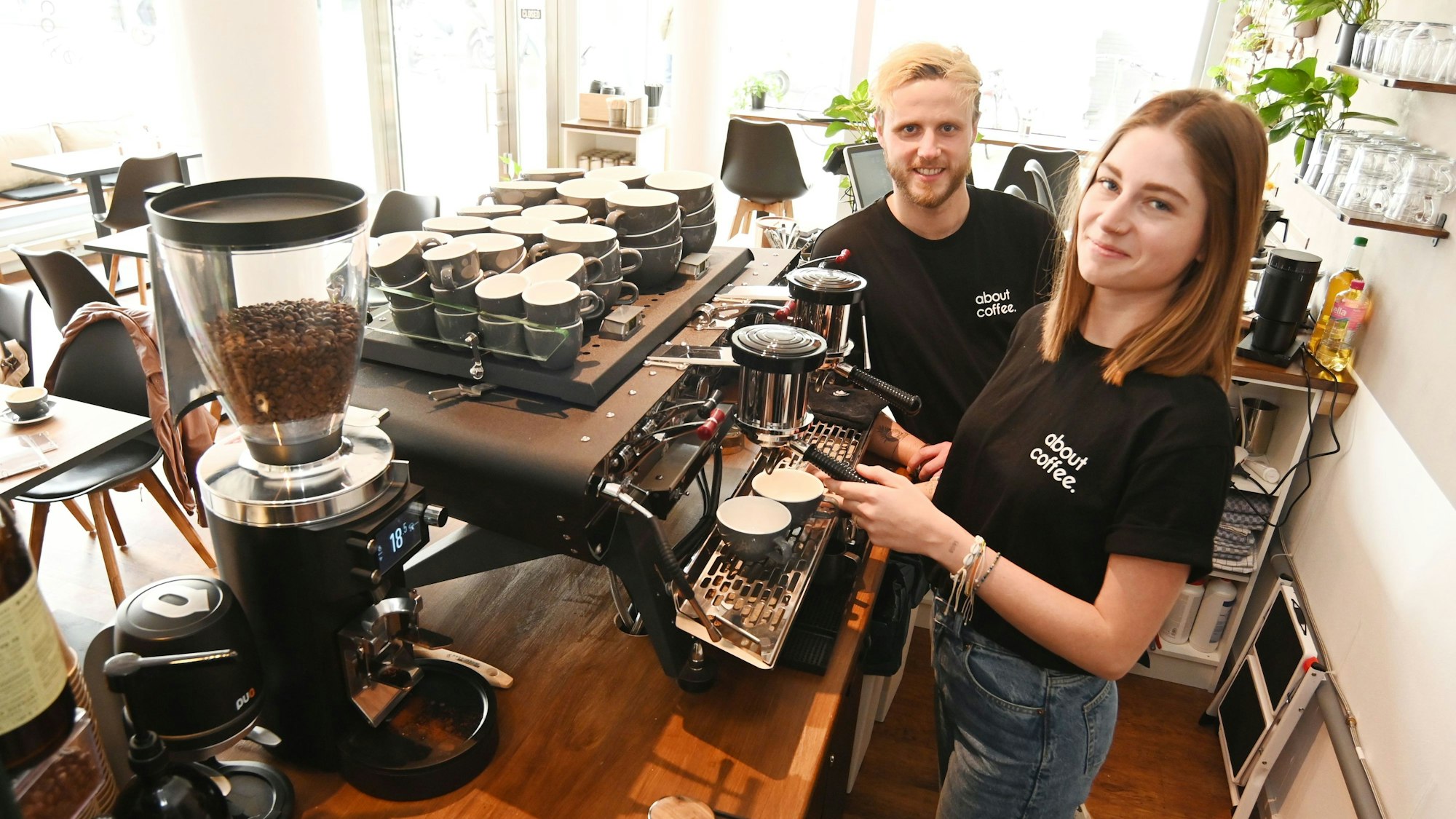 Das Ehepaar schaut von einer Siebträgermaschine aus in die Kamera.