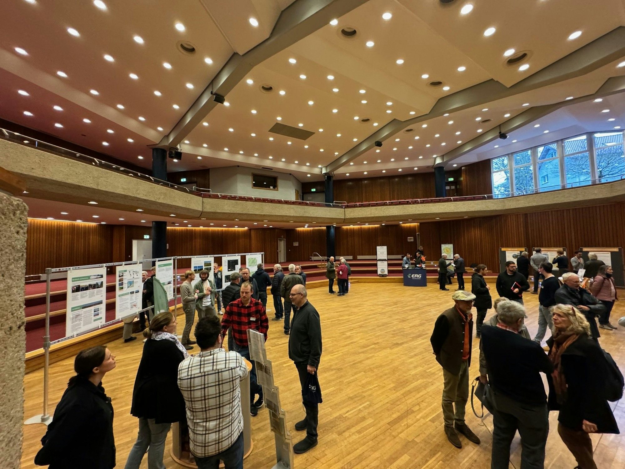 Menschen stehen in einem großen Saal vor Stellwänden.