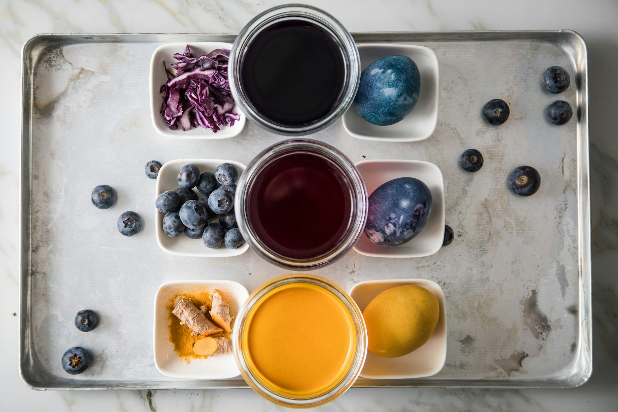 Verschiedene Töpfe mit einem Sud zum Eier färben stehen auf einem Tablett.