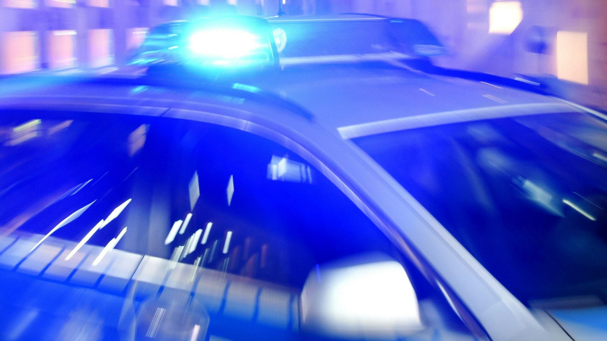 ARCHIV - 06.08.2015, Schleswig-Holstein, Flensburg: Ein Streifenwagen der Polizei steht mit eingeschaltetem Blaulicht auf der Straße.