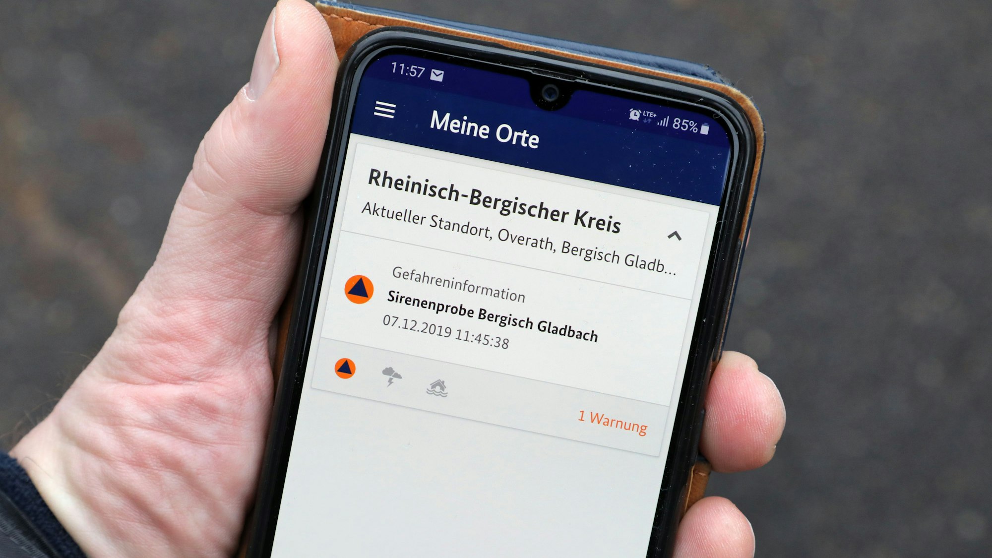Eine Hand hält ein Smartphone mit einer Siorenenproben-Meldung.
