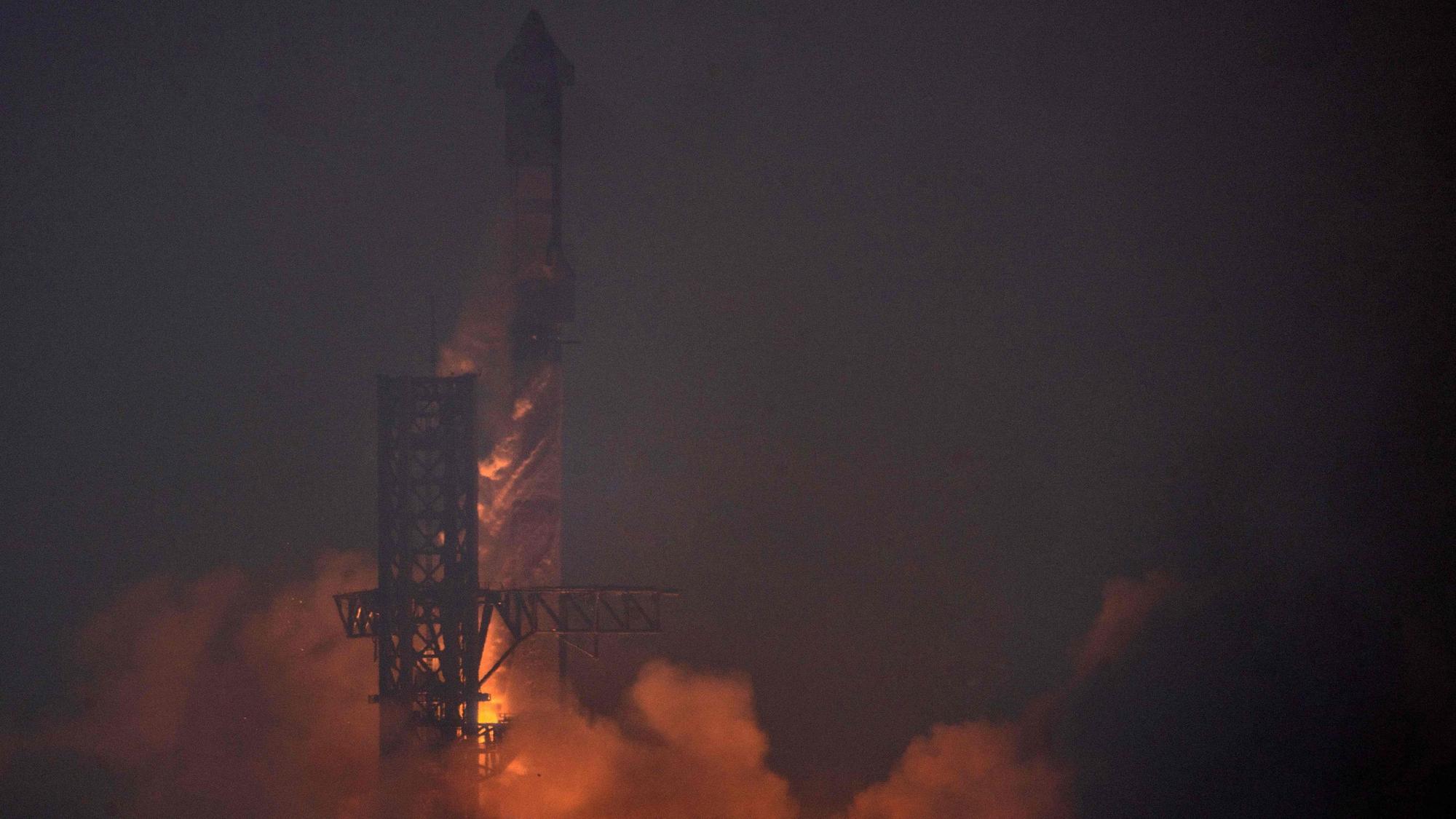 Im Dunkeln findet ein Raketenstart statt, dessen Antrieb die entstehende Rauchentwicklung beleuchtet.