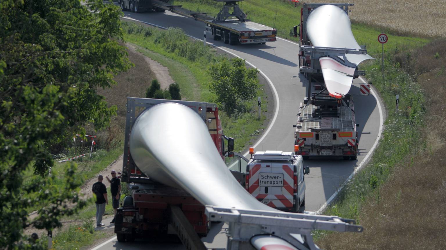 Ein Konvoi von Transportern mit Windradflügeln steckt am 10.07.2014 auf der Straße von Wöllstein nach Neu-Bamberg (beides Rheinland-Pfalz) fest. Der erste von sechs Großtransportern mit Windradflügeln ist in einer Kurve in Rheinhessen steckengeblieben. So war die Kolonne vor dem Ort Neu-Bamberg unfreiwillig zu einer Pause gezwungen worden. Foto: Fredrik von Erichsen/dpa ++ +++ dpa-Bildfunk +++