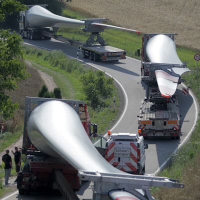 Ein Konvoi von Transportern mit Windradflügeln steckt am 10.07.2014 auf der Straße von Wöllstein nach Neu-Bamberg (beides Rheinland-Pfalz) fest. Der erste von sechs Großtransportern mit Windradflügeln ist in einer Kurve in Rheinhessen steckengeblieben. So war die Kolonne vor dem Ort Neu-Bamberg unfreiwillig zu einer Pause gezwungen worden. Foto: Fredrik von Erichsen/dpa ++ +++ dpa-Bildfunk +++