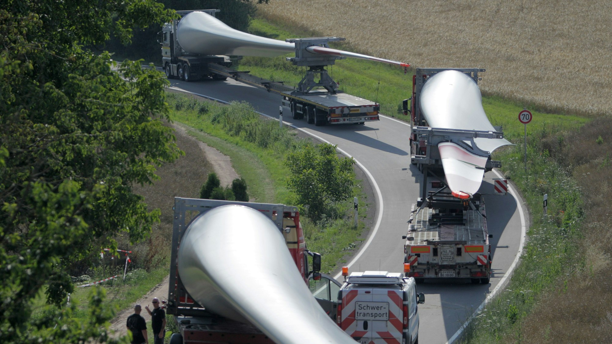 Ein Konvoi von Transportern mit Windradflügeln steckt am 10.07.2014 auf der Straße von Wöllstein nach Neu-Bamberg (beides Rheinland-Pfalz) fest. Der erste von sechs Großtransportern mit Windradflügeln ist in einer Kurve in Rheinhessen steckengeblieben. So war die Kolonne vor dem Ort Neu-Bamberg unfreiwillig zu einer Pause gezwungen worden. Foto: Fredrik von Erichsen/dpa ++ +++ dpa-Bildfunk +++