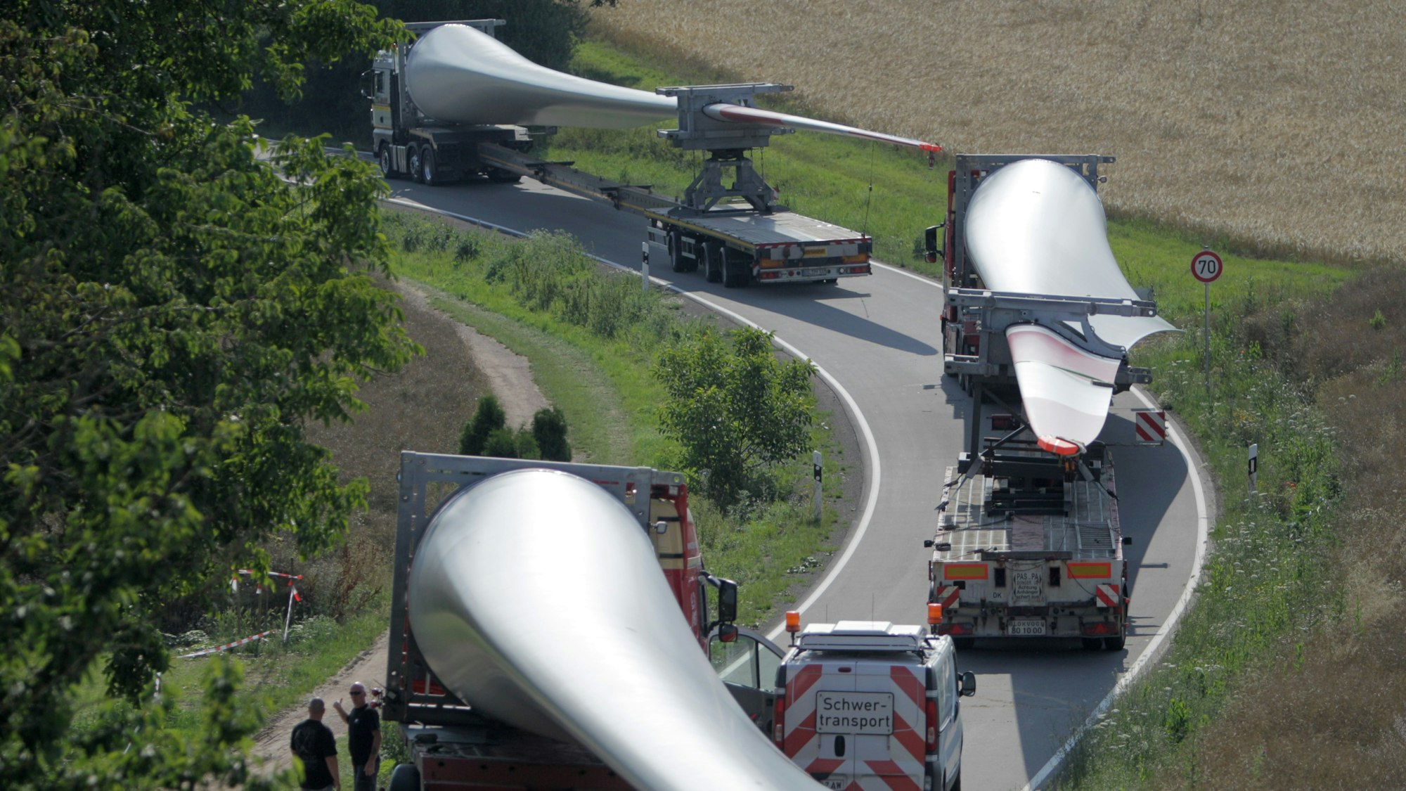 Ein Konvoi von Transportern mit Windradflügeln steckt am 10.07.2014 auf der Straße von Wöllstein nach Neu-Bamberg (beides Rheinland-Pfalz) fest. Der erste von sechs Großtransportern mit Windradflügeln ist in einer Kurve in Rheinhessen steckengeblieben. So war die Kolonne vor dem Ort Neu-Bamberg unfreiwillig zu einer Pause gezwungen worden. Foto: Fredrik von Erichsen/dpa ++ +++ dpa-Bildfunk +++