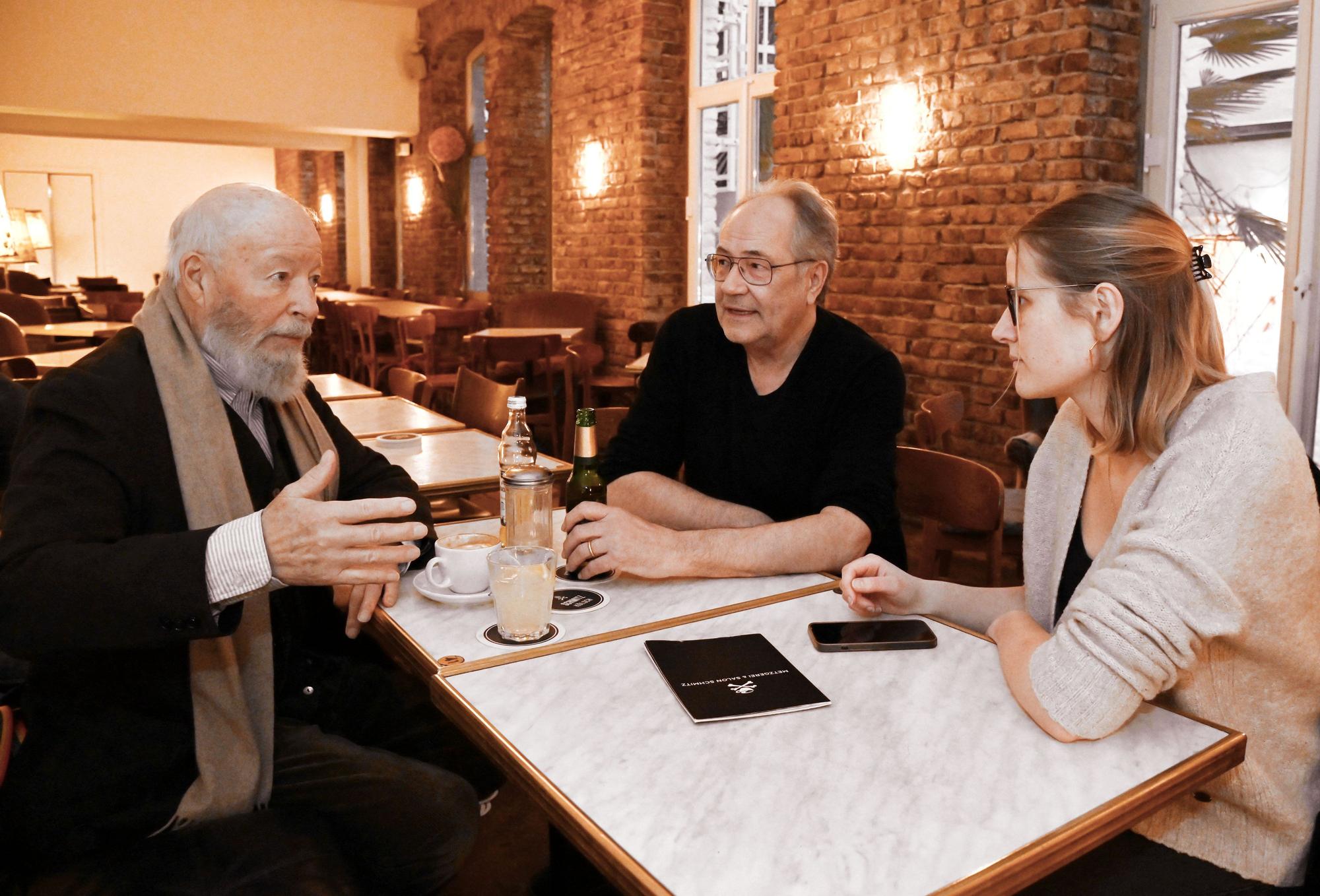 Bill Mockridge und Hartmut Volle sitzen mit einer Redakteurin an einem Tisch im Salon Schmitz.