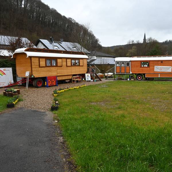 Zwei Zirkuswagen stehen auf einer Wiese in Gemünd. Darin wird der Malzirkus für Kinder aus von der Flutkatastrophe betroffenen Familien angeboten.