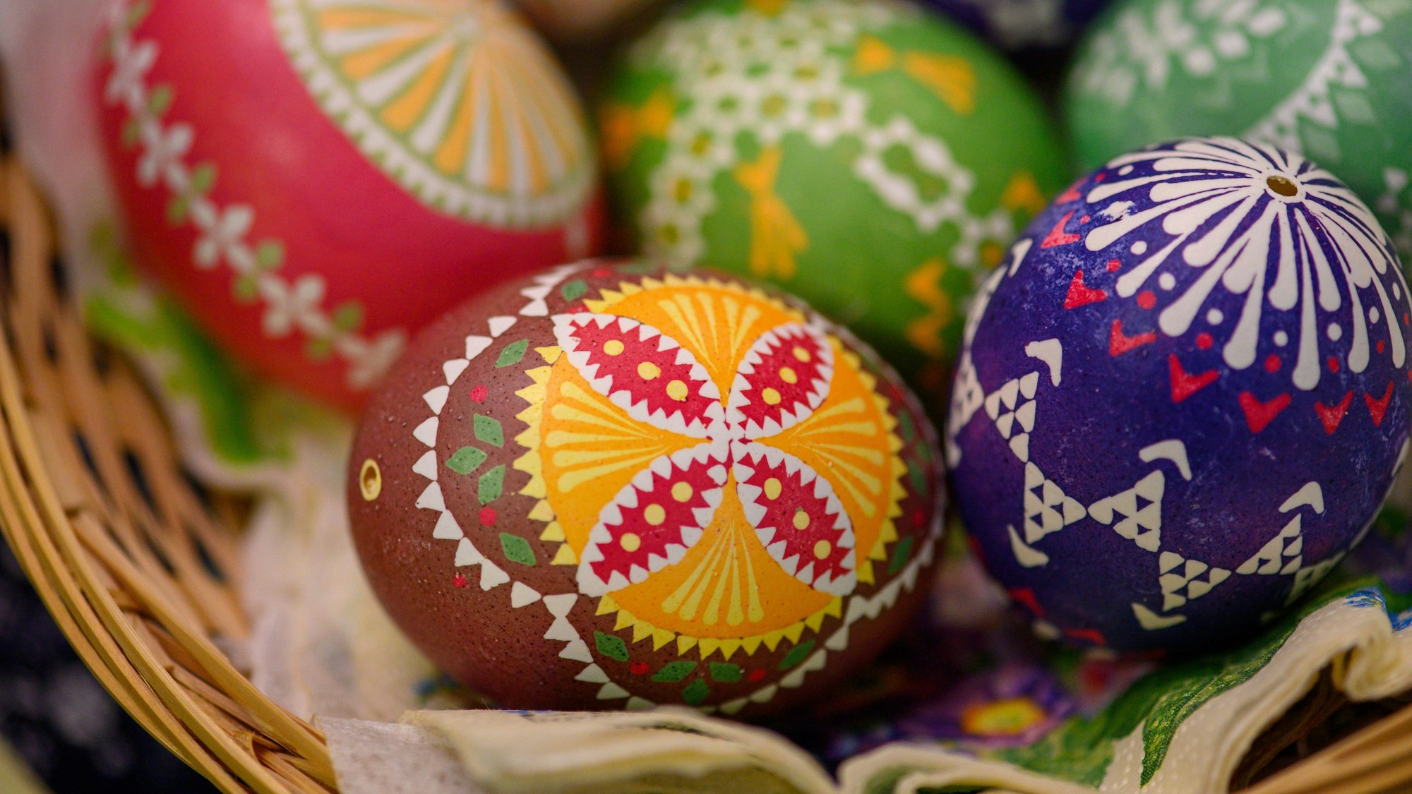 Ostereier mit bunten Verzierungen liegen in einem Korb.