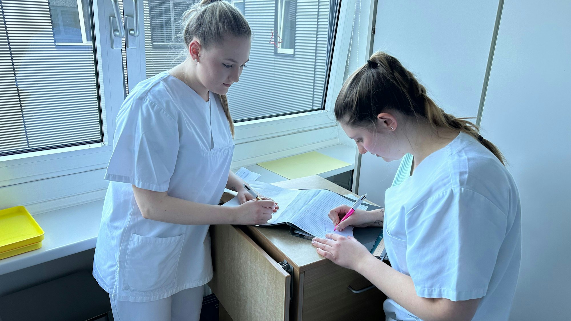 Zwei Auszubildende überprüfen eine Medikamentenliste.