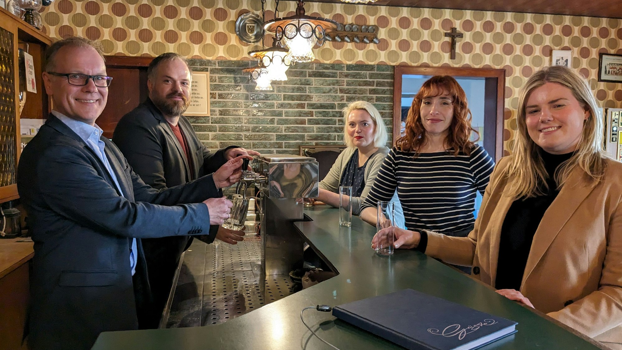 In der Gaststätte Watteler in der Baugruppe Marktplatz Rheinland stehen Museumschef Dr. Carsten Vorwig und Daniel Manner an der Zapfanlage. Margarethe Becker, Ann Heinen und Alina Hilbrecht (v.l.) stehen an der Theke.