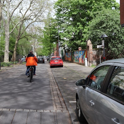 Blick auf eine schmale Straße, auf der gerade ein Radfahrer unterwegs ist