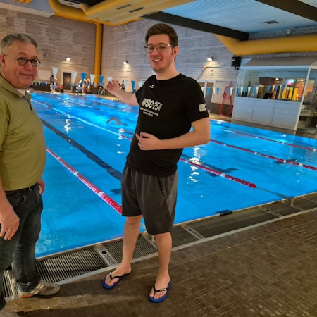 Bild von zwei Männern, im Hintergrund ein Schwimmbecken