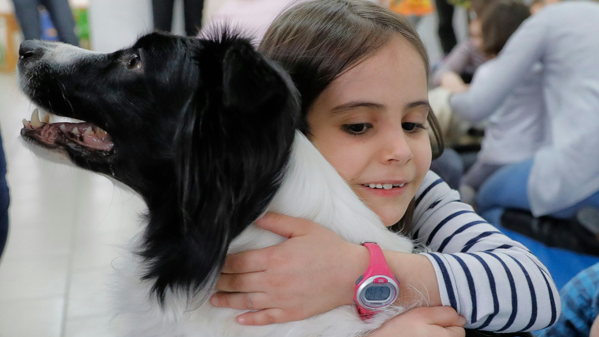 Das Foto zeigt ein Kind, das einen Hund umarmt.