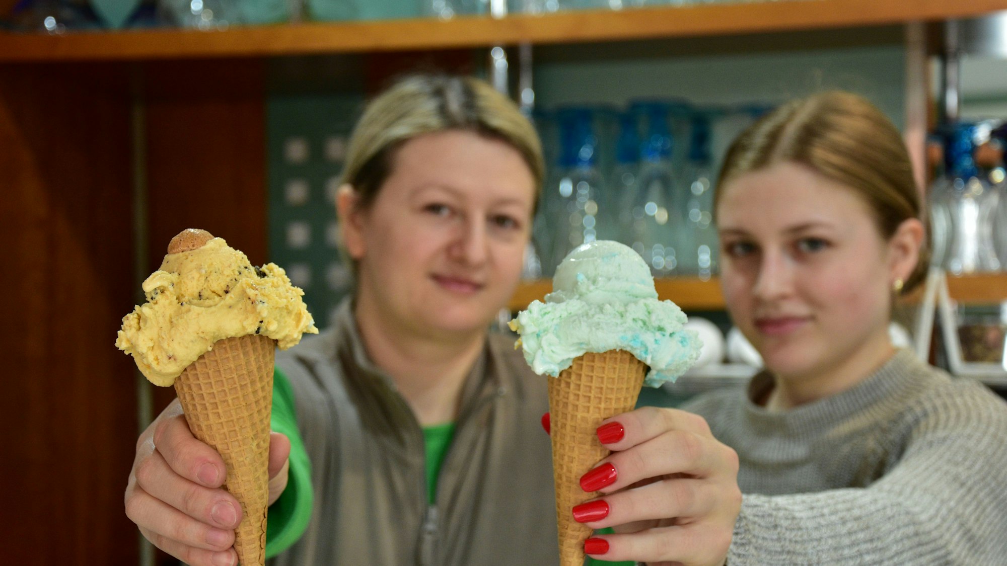 Test Eisdielen, Eiscafé Il Paradiso in Much: Inhaberin Anca Lazar (l.) hat das traditionelle Mucher Eis in der Hand (enthält Liköre und Amarettini), Mitarbeiterin Rebecca Ciocoiu hält das Zuckerwatte-Eis in der Hand, und es schmeckt haargenau wie der Kirmes-Snack