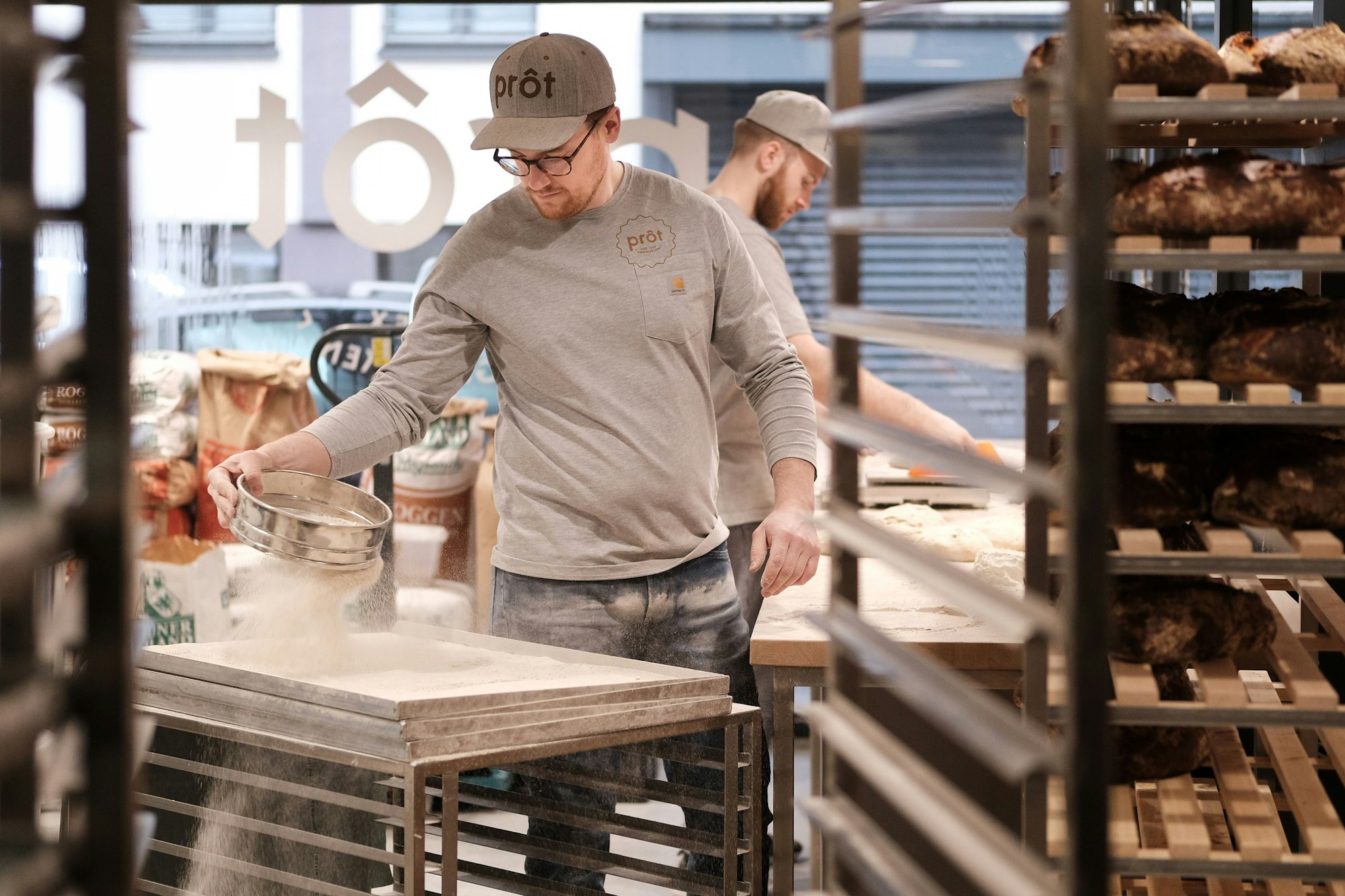 Alexander Onasch in seiner Backstube, umgeben von mehreren Blechen mit Brot.