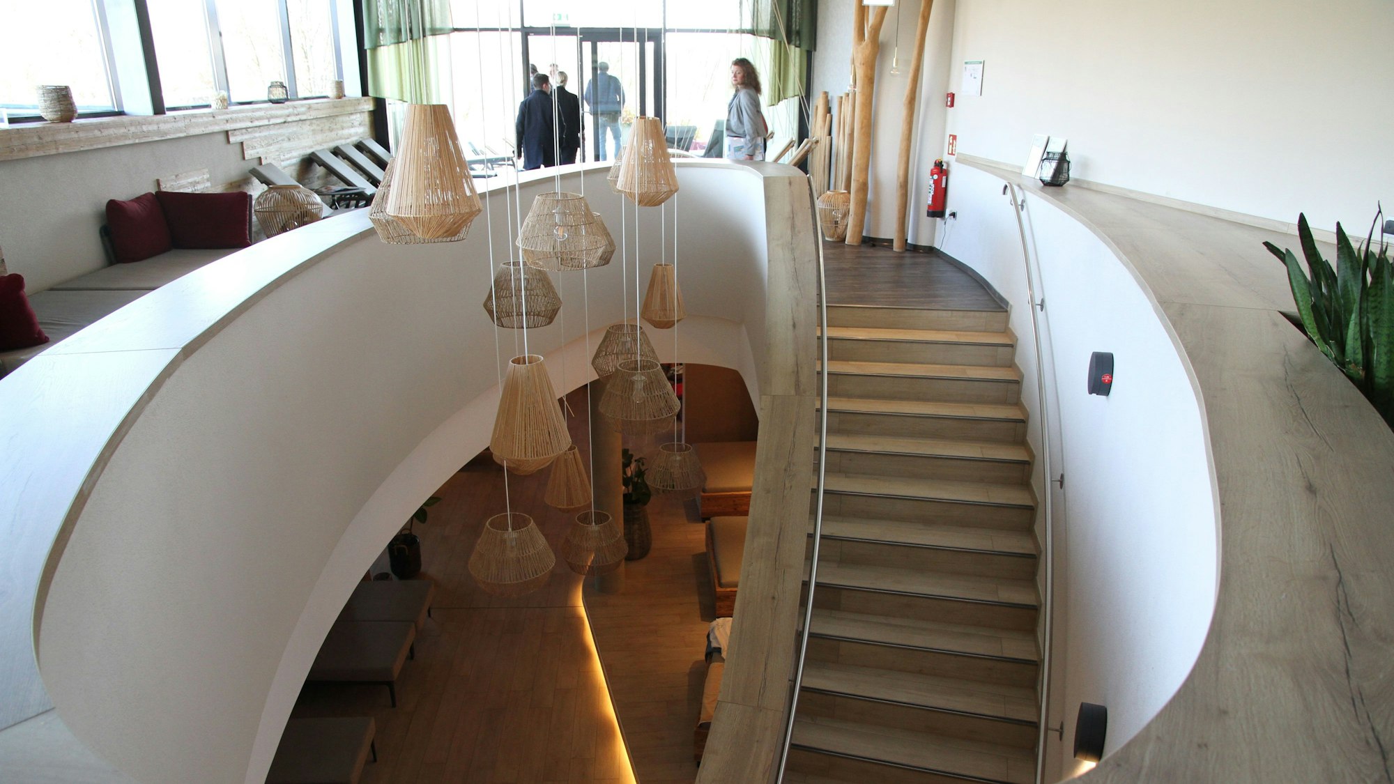 Eine geschwungene Treppe führt aus dem Erdgeschoss einer Sauna in das Obergeschoss.