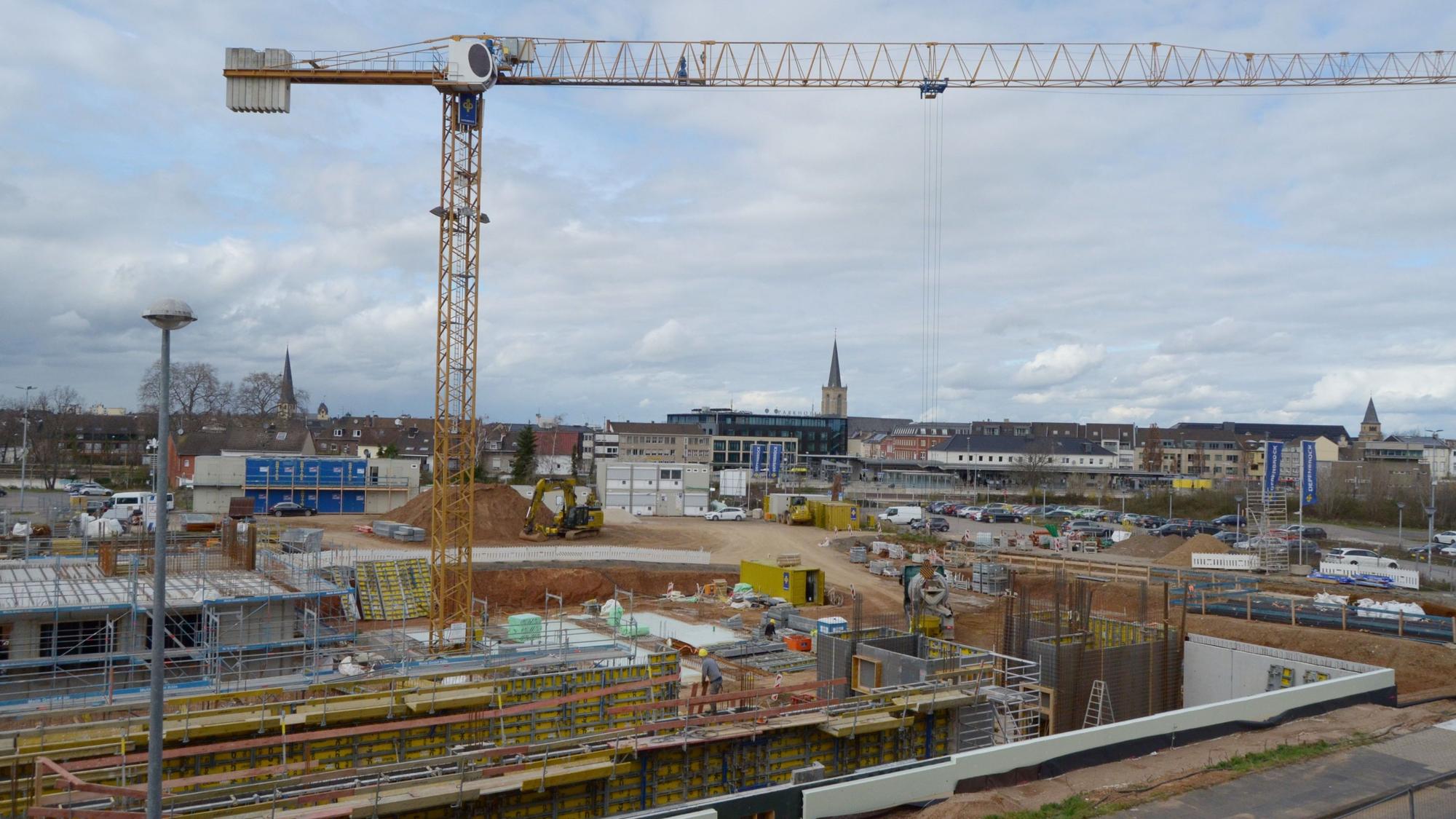 Das Eckgrundstück Roitzheimer Straße/An der Vogelrute ist eine Großbaustelle, im Hintergrund erkennt man den Bahnhof und die drei Kirchen in der Euskirchener Innenstadt.