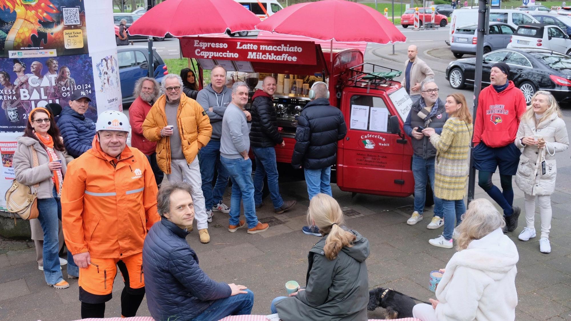 Viele Menschen stehen um eine knallrote mobile Kaffeebar.