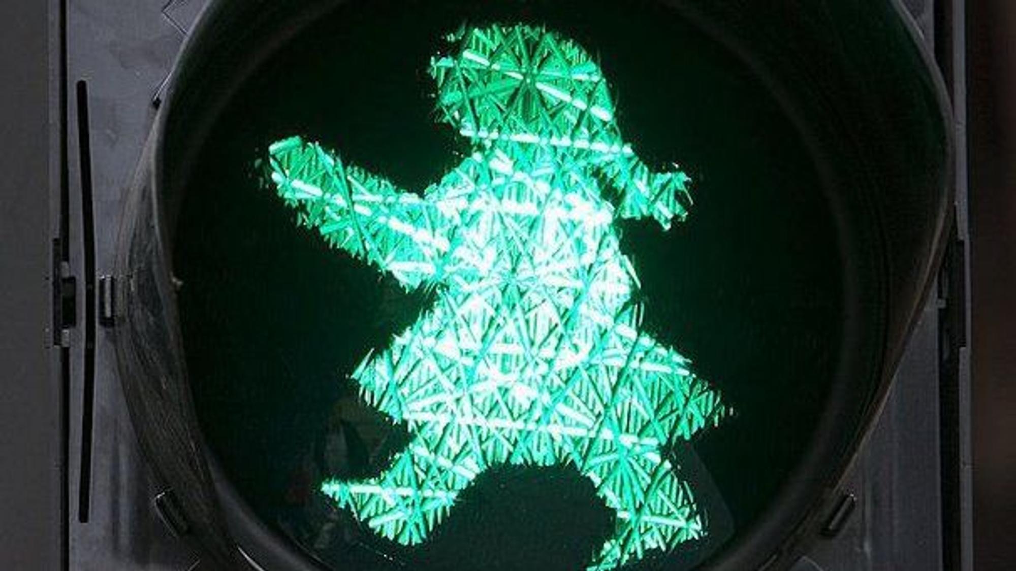 Eine Ampelfrau als Lichtzeichen mit einem stilisierten Haarzopf und einem Rock.