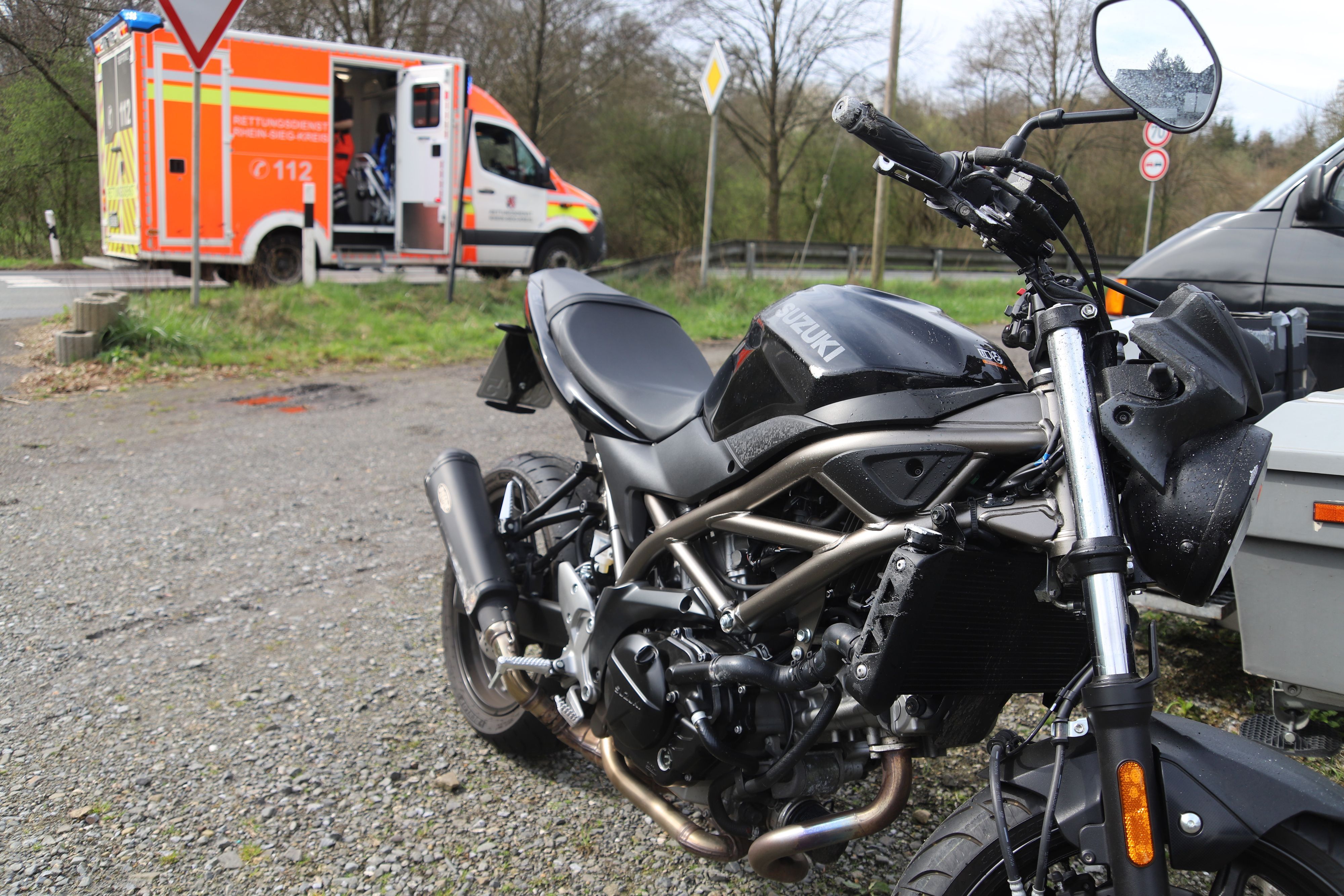 Ein schwarzes Motorrad steht in der Nähe eines Rettungswagens.