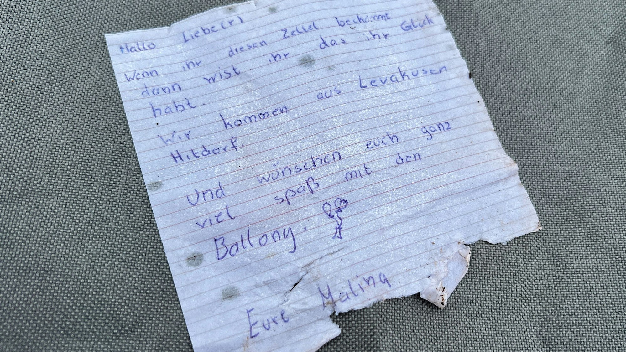 Zettel mit Glückwünschen, der wohl an einem Ballon hing.