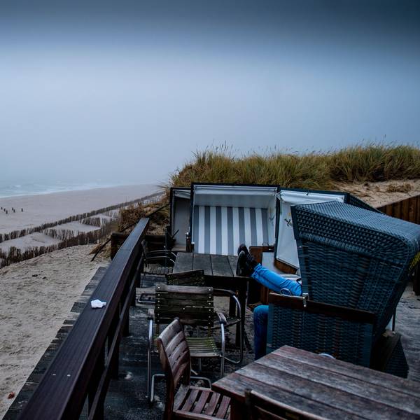Zwei Besucher sitzen in einem Strandkorb am Strand von Rantum auf Sylt.