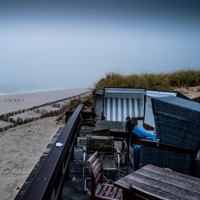 Zwei Besucher sitzen  in einem Strandkorb am Strand von Rantum auf Sylt.