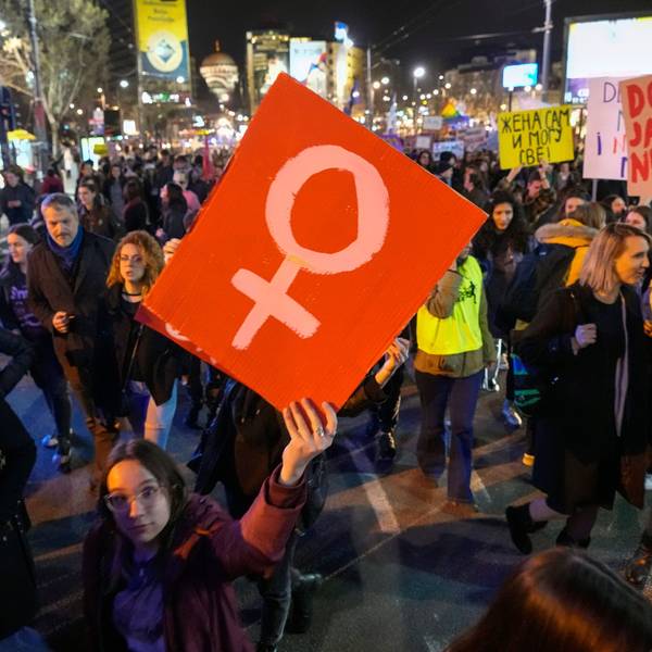 Das Bild zeigt eine demonstrierende Frau, die ein Schild in die Höhe reckt.