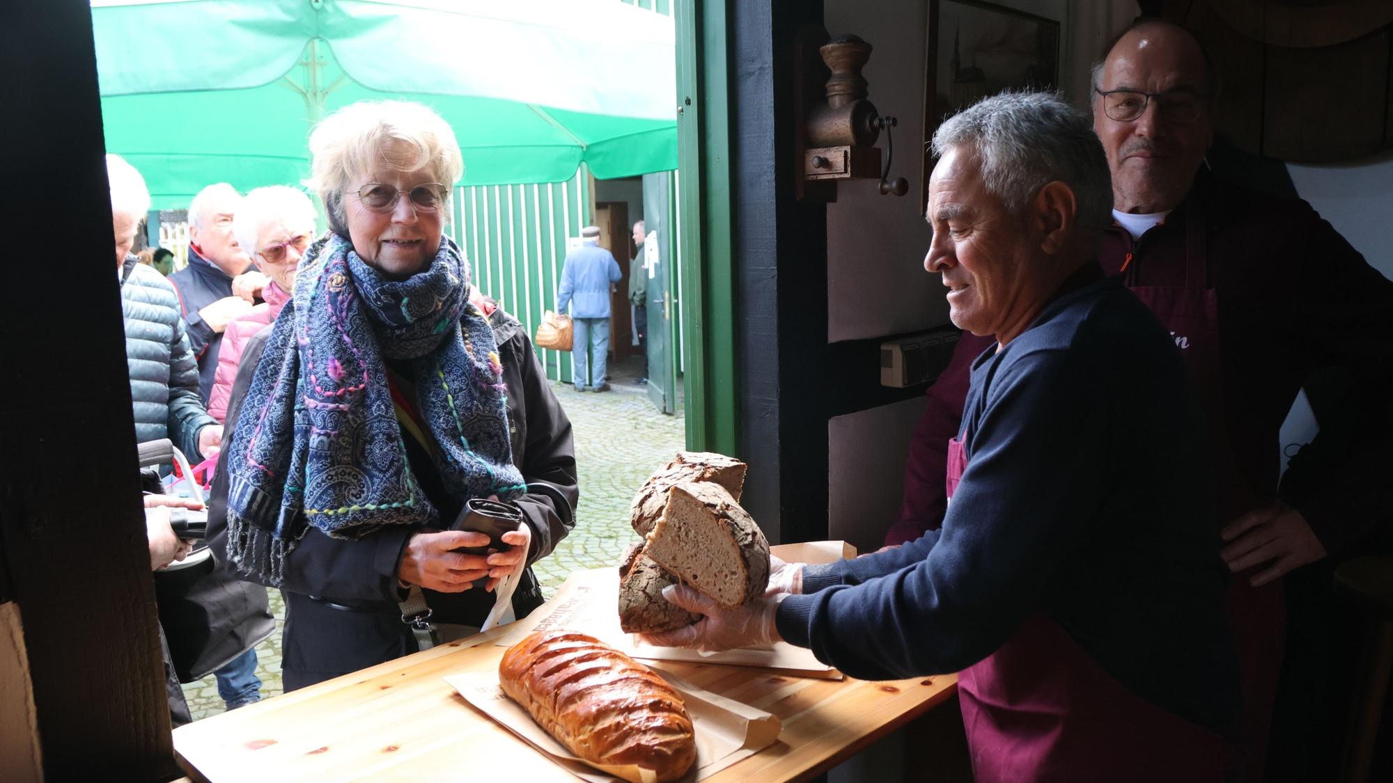Ein Mann packt einer Frau Brot ein.