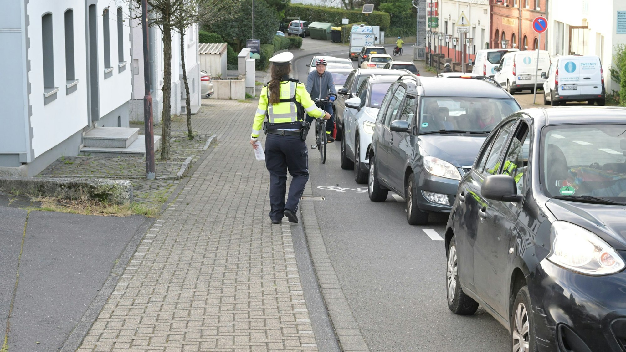 Bei der Aktion "Mehr Miteinander im Verkehr" beobachtet eine Polizistin den Rad-Schutzstreifen 
auf der Bensberger Straße in Forsbach.