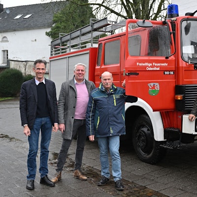 Ein Löschfahrzeug der Feuerwehr, davor vier Männer.
