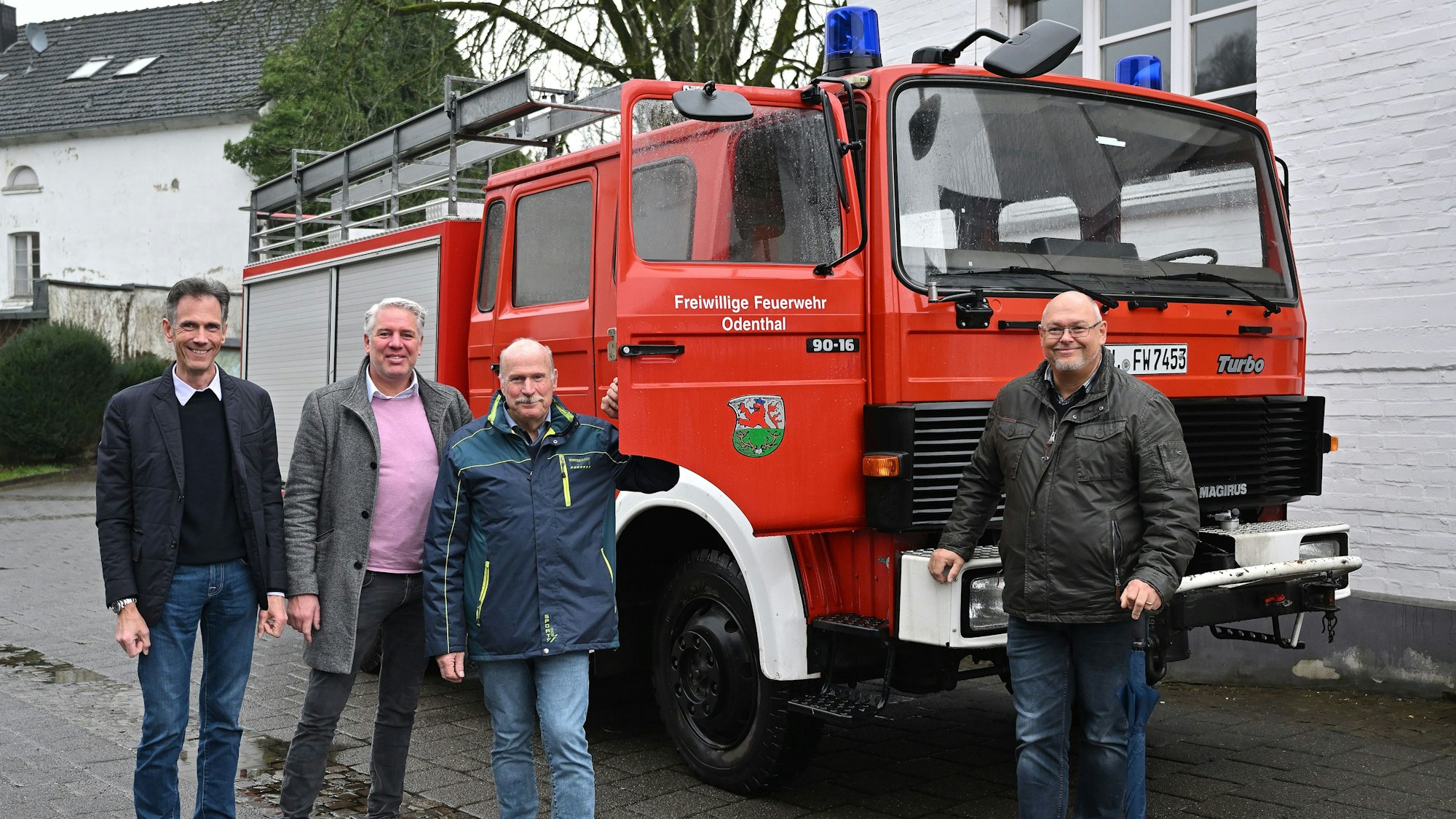 Ein Löschfahrzeug der Feuerwehr, davor vier Männer.