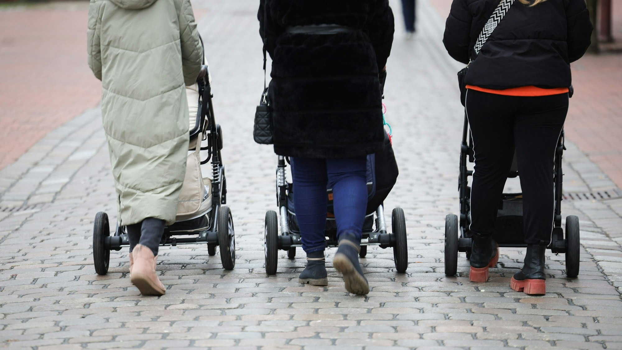 Drei Frauen schieben Kinderwagen vor sich her. Man sieht sie von hinten.