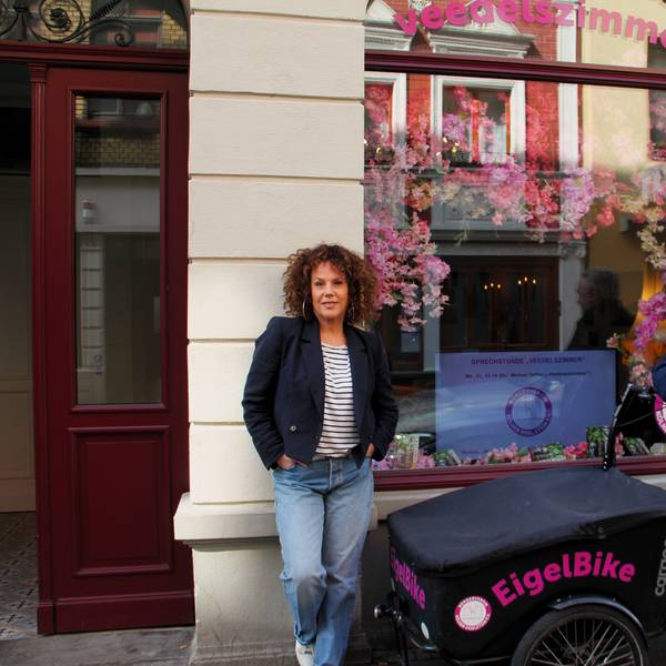 Eine Frau mit gelocktem Haar und ein Mann mit grauem Haar stehen neben einem Lastenrad mit der Aufschrift EigelBike.