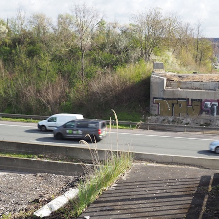 Zu sehen ist eine Autobahn, von der Brücke, die einmal darüber verlief, stehen nur noch die Pfeiler.