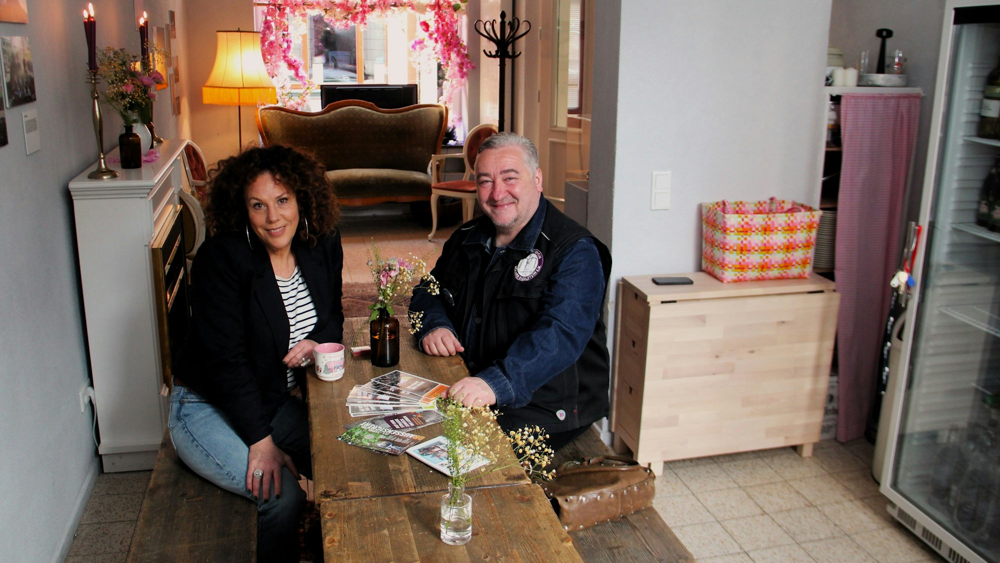 Eine Frau und ein Mann sitzen an einem Holztisch.