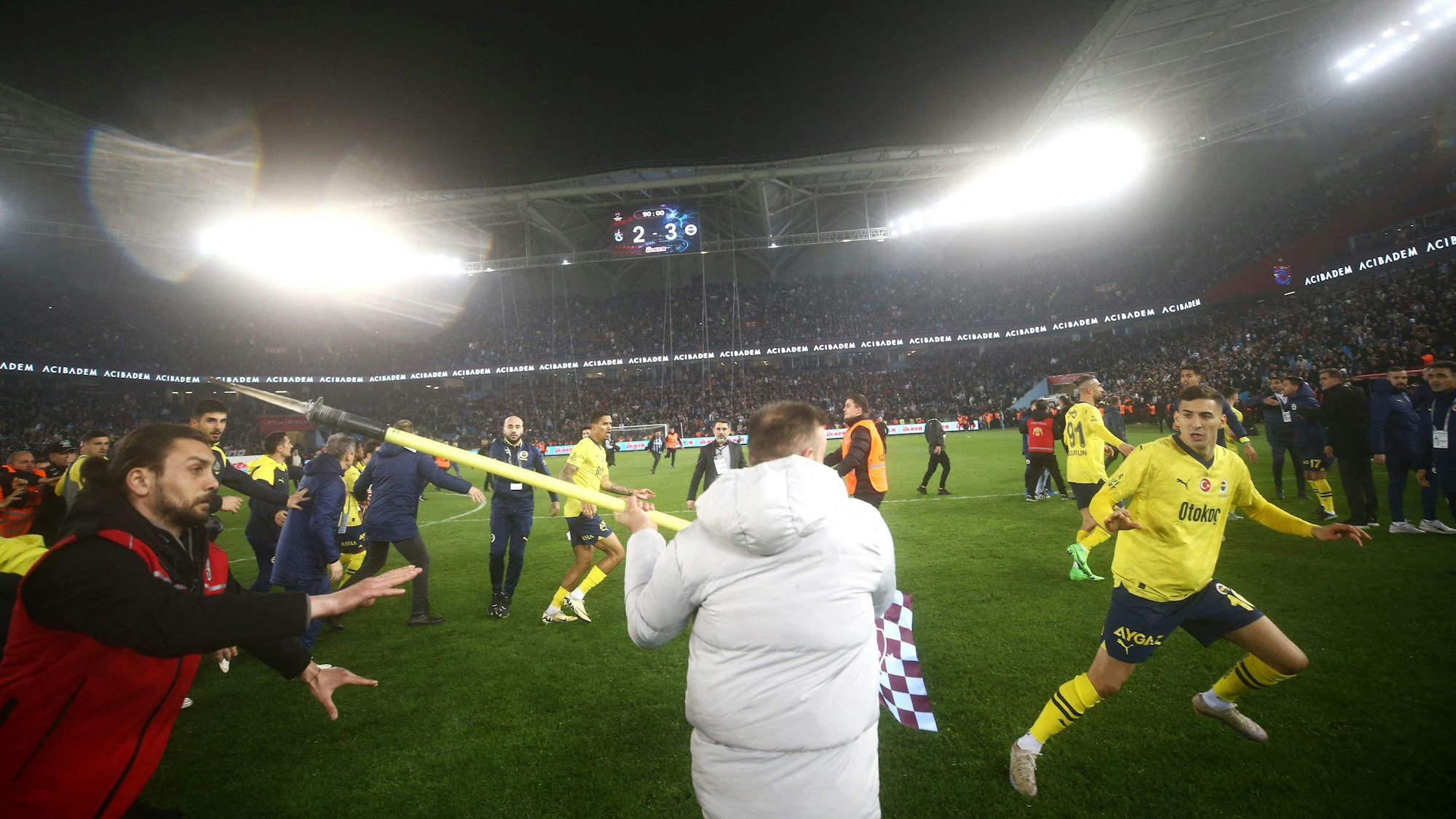 Ein Fan geht mit der spitzen Seite einer Eckfahne auf die Spieler los.