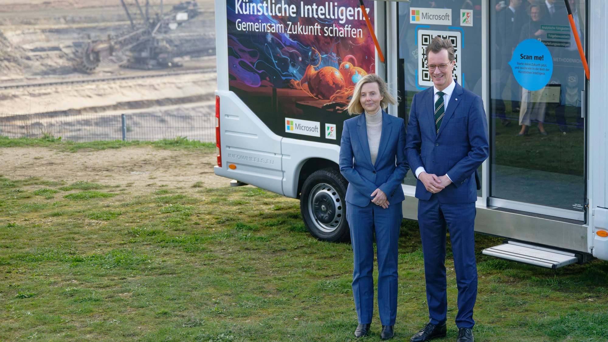 18.03.2024, Nordrhein-Westfalen, Elsdorf: Marianne Janik (l), Vorsitzende der Geschäftsführung von Microsoft Deutschland, und Hendrik Wüst, Ministerpräsident des Landes Nordrhein-Westfalen (CDU), stehen vor einer Pressekonferenz zum Thema «Von der Kohle zur KI» am Rand des Tagebau Hambach vor einem Fahrzeug, mit dem für KI-Fortbildung geworben wird. Foto: Henning Kaiser/dpa +++ dpa-Bildfunk +++
