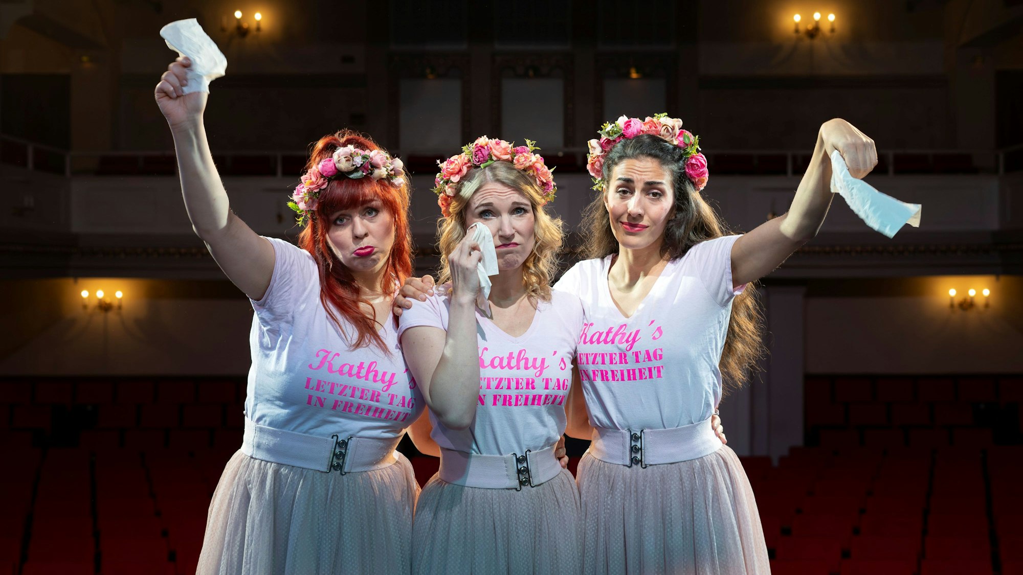 Drei Schauspielerinnen winken traurig mit Taschentüchern in die Kamera.
