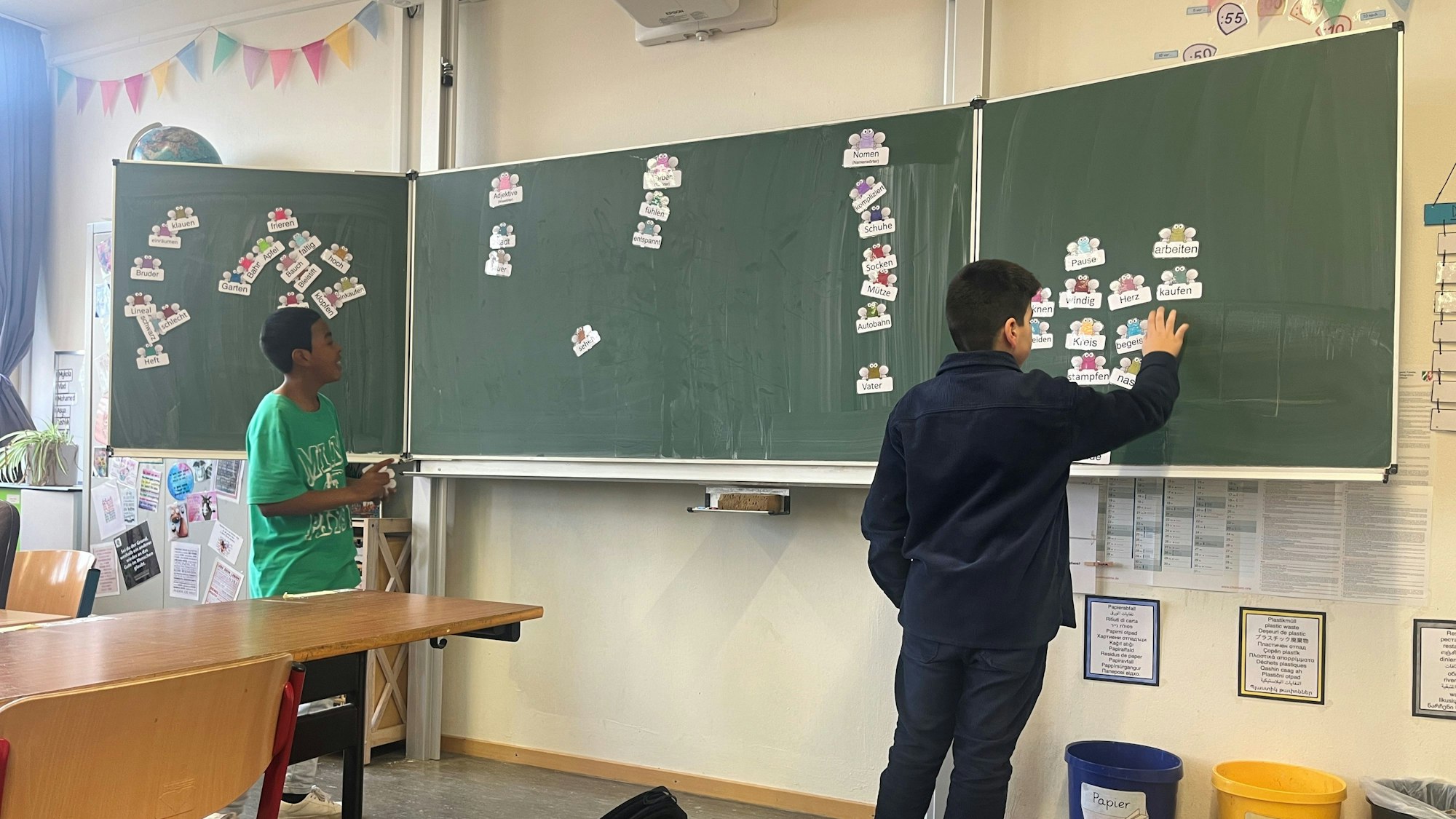 Joshua (l.) und ein Mitschüler spielen gemeinsam ein Wortspiel an der Tafel.