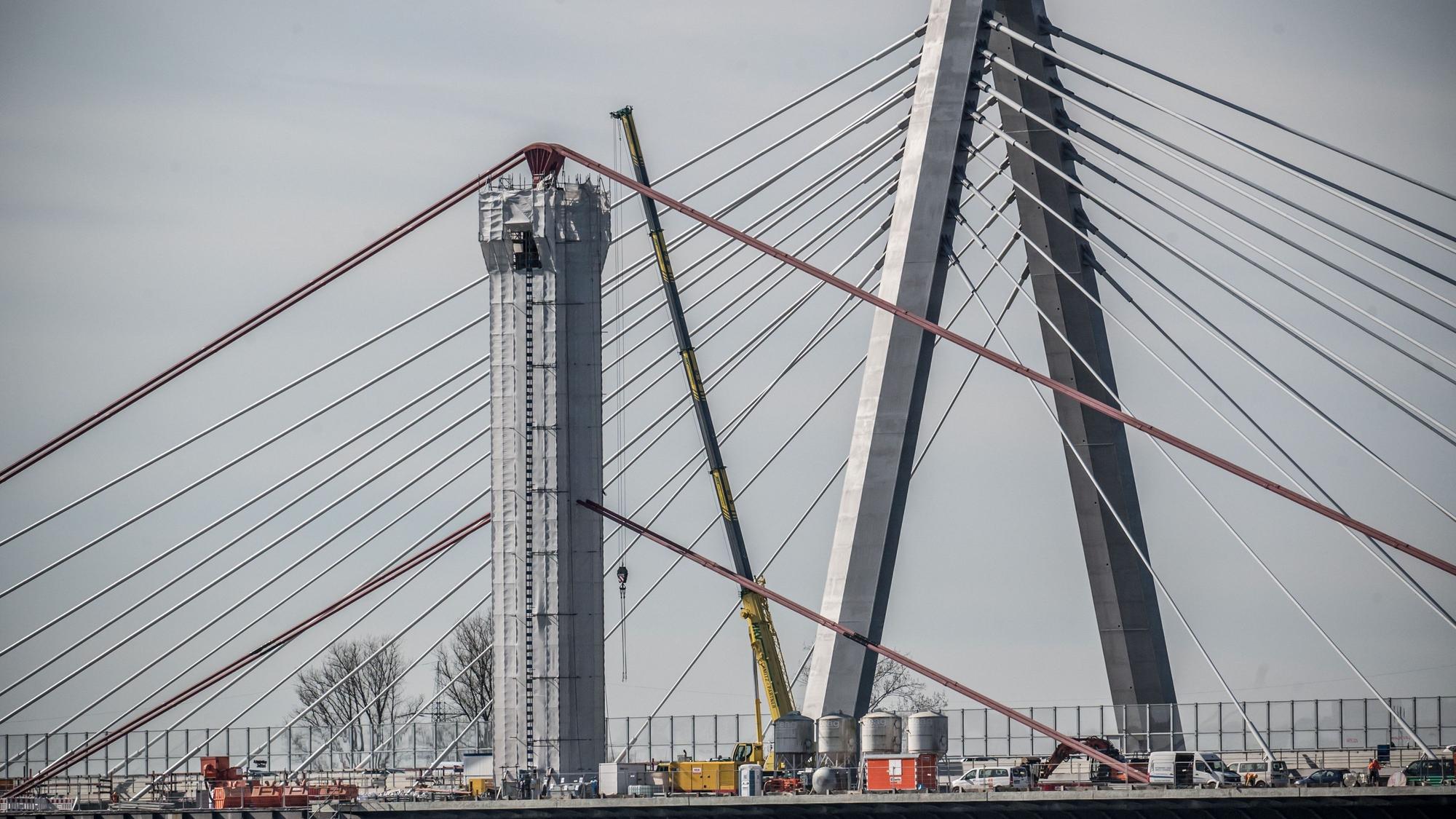 Der Abbruch der alten Autobahnbrücke läuft: Von den alten Pylonen wurde oben die Verkleidung abgenommen, die gerundeten Seilsättel sind seither sichtbar. Der Stahl ist mit bleihaltigem Schutzanstrich versehen.