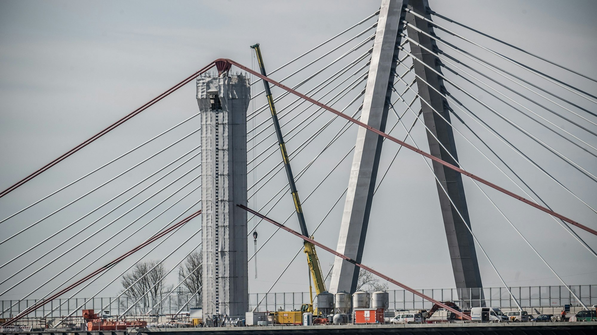 Der Abbruch der alten Autobahnbrücke läuft: Von den alten Pylonen wurde oben die Verkleidung abgenommen, die gerundeten Seilsättel sind seither sichtbar. Der Stahl ist mit bleihaltigem Schutzanstrich versehen.