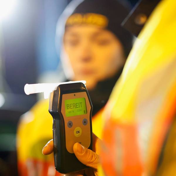 Eine Polizistin misst den Atemalkoholgehalt eines Autofahrers mit einem Alkoholtester, um festzustellen, ob er möglicherweise unter Alkoholeinfluss steht.
