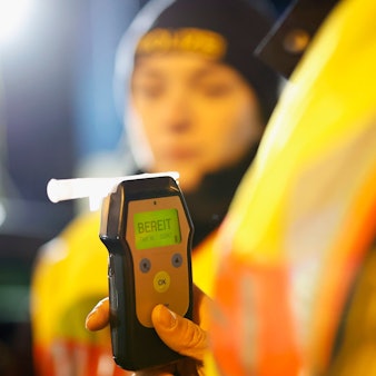 Eine Polizistin misst den Atemalkoholgehalt eines Autofahrers mit einem Alkoholtester, um festzustellen, ob er möglicherweise unter Alkoholeinfluss steht.