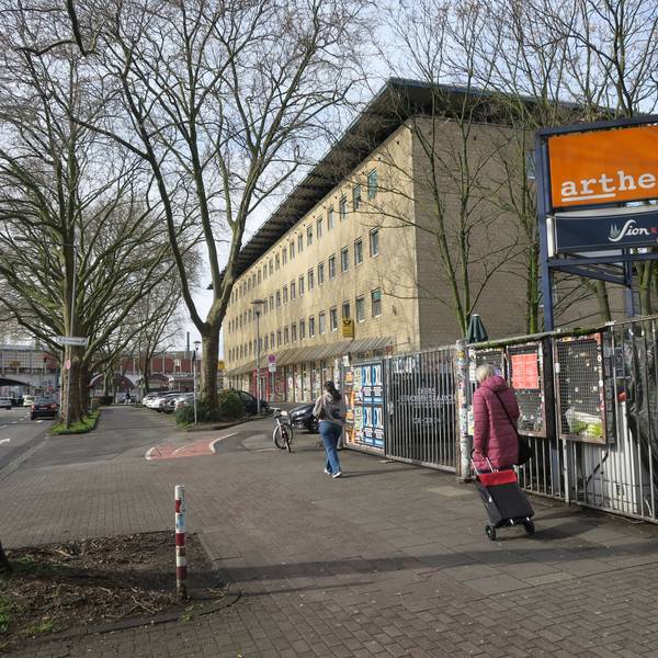 Blick auf ein mehrgeschossiges Gebäude mit gelber Fassade, im Vordergrund ist der Eingang zum Artheater.