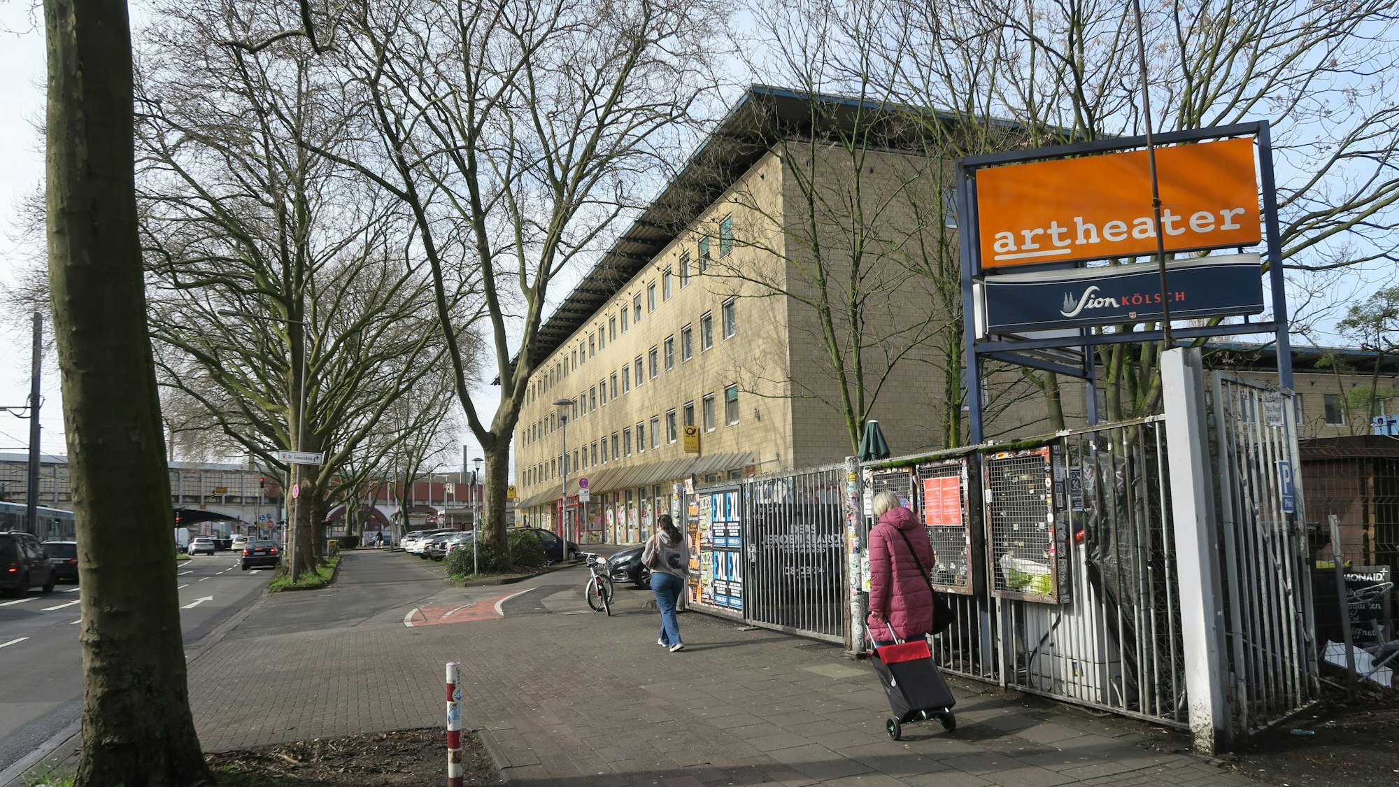 Blick auf ein mehrgeschossiges Gebäude mit gelber Fassade, im Vordergrund ist der Eingang zum Artheater.