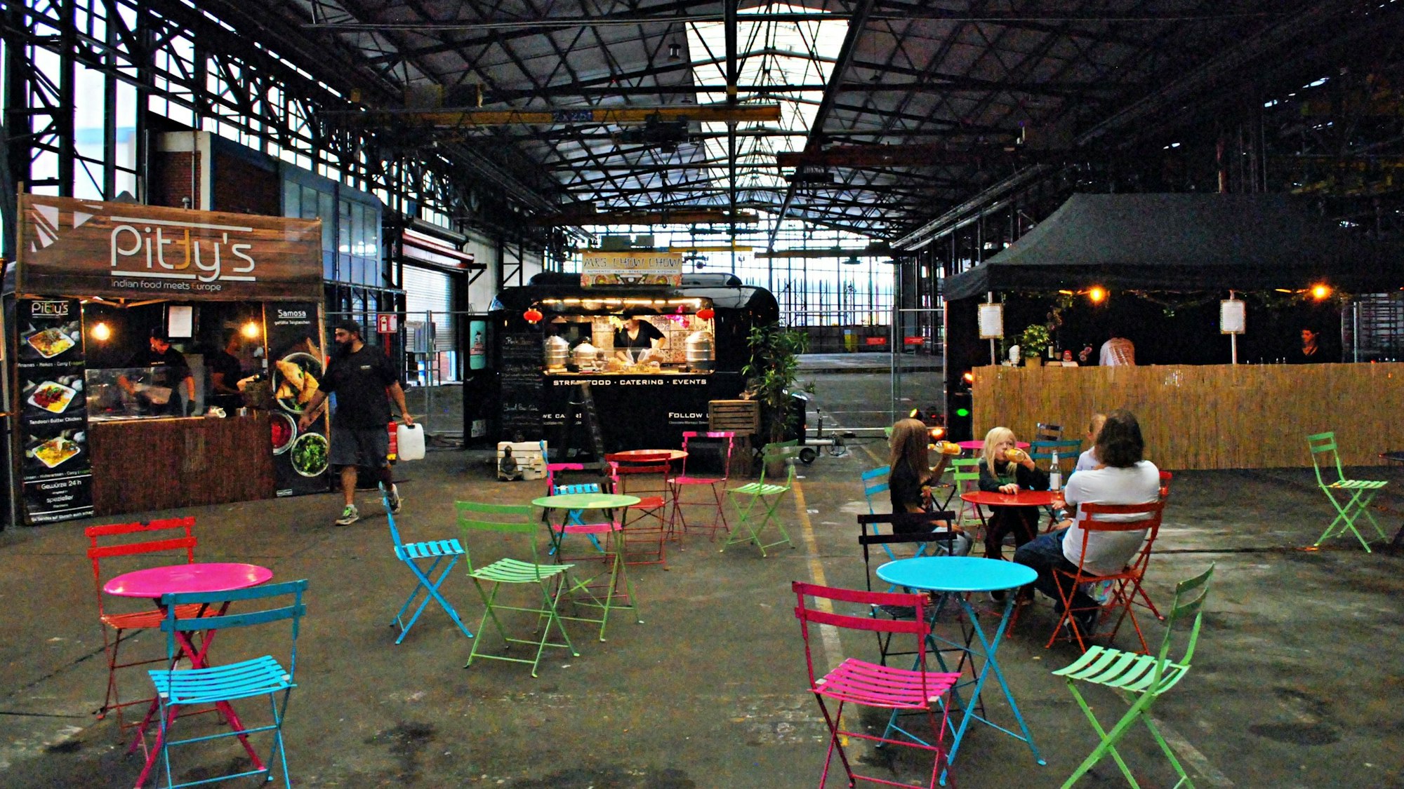 Eine Markthalle mit Imbissständen, Stühlen und Tischen