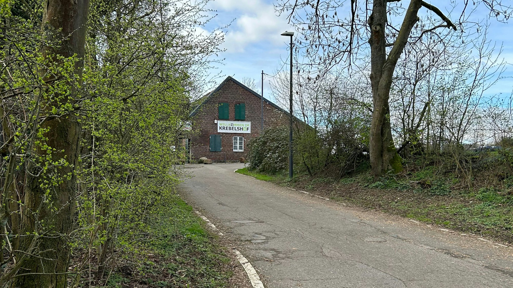 Blick auf eine Straße, die zu einem Bauernhof-Gebäude führt.