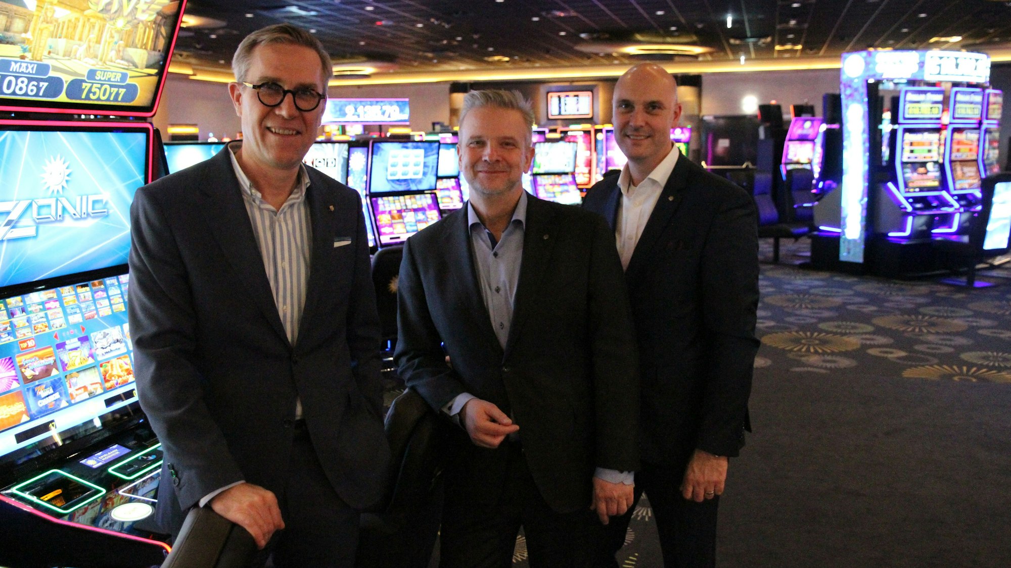 Drei Männer vor Spielautomaten